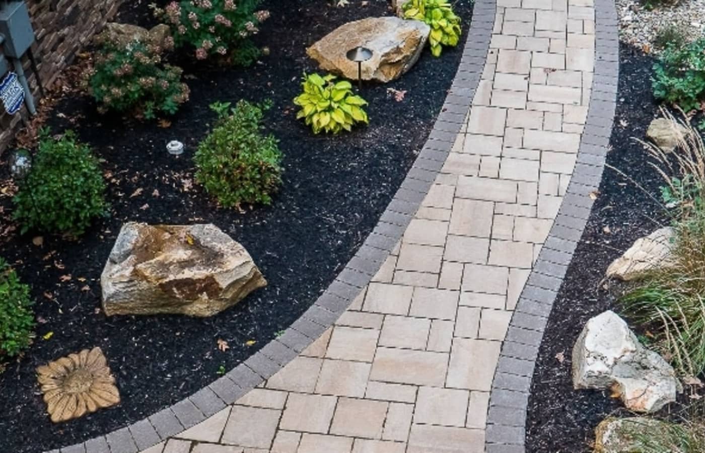 Paver walkway with a charcoal soldier course running through planted beds