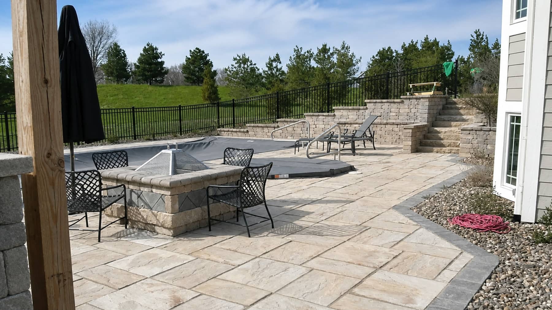 Paver patio with a seating wall and a fenced yard beyond it