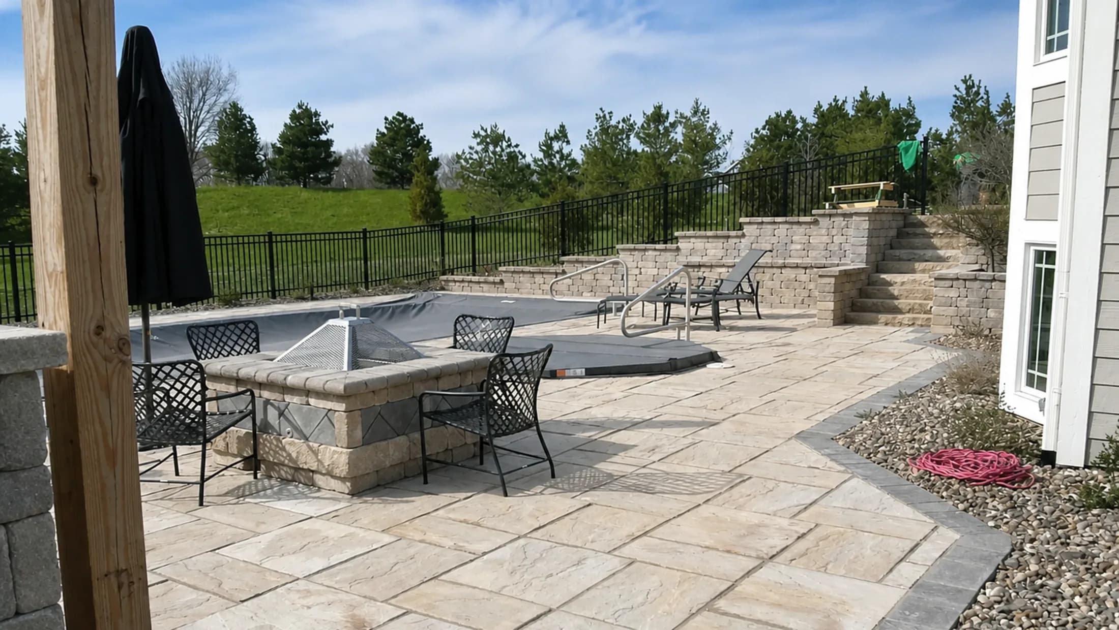 Paver patio with a seating wall and a fenced yard beyond it