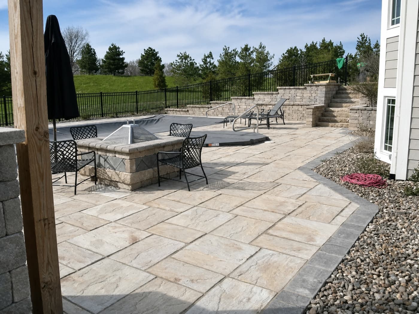 Paver patio with a seating wall and a fenced yard beyond it