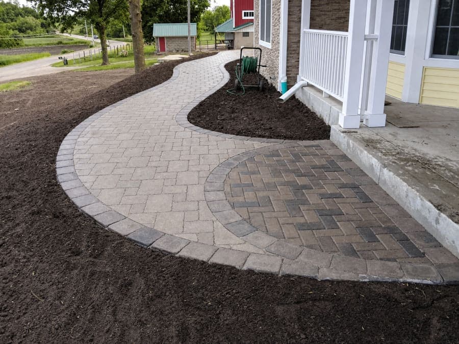 Paver walkway curving to a front entry with fresh mulch beds